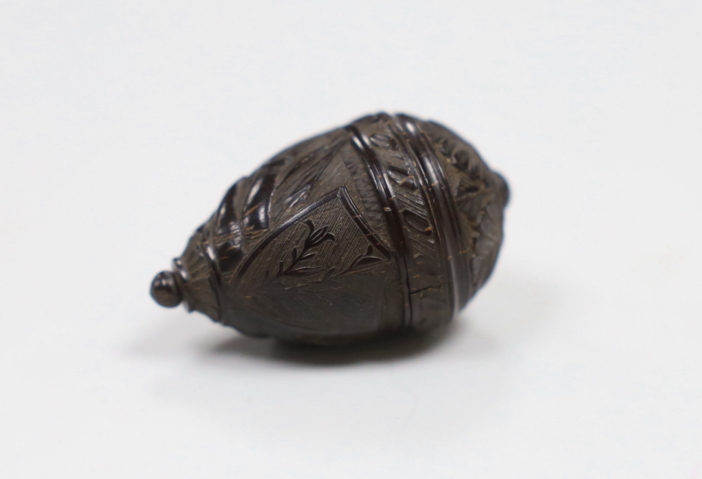 A 19th century sailor carved scrimshaw nut depicting an anchor and ship's cannon, 3.5cm high